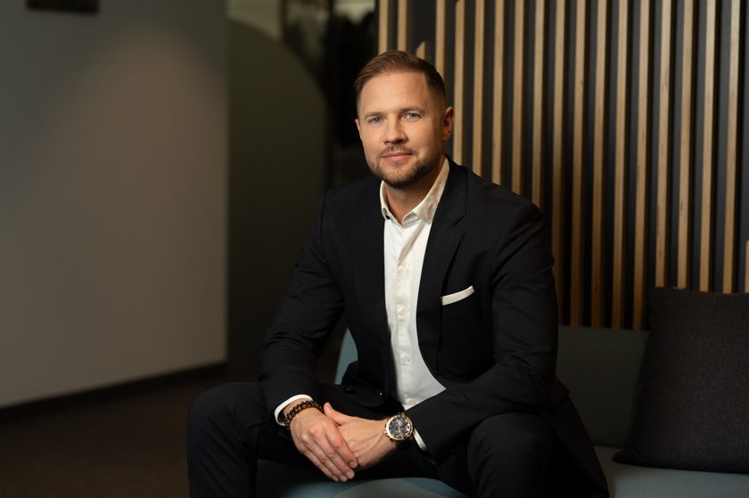 Allan Valm, AI Augmentation Partner and Partner at Helmes, seated in a dark suit and white shirt